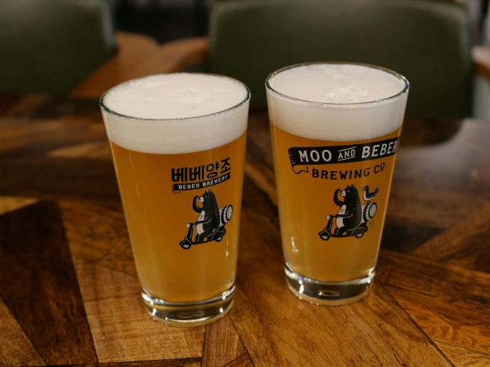 two glasses of beer sitting on top of a wooden table